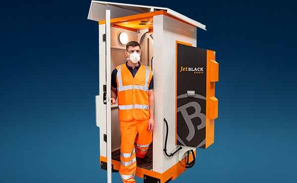 Eine Person in Arbeitskleidung verlässt die JetBlack Personendusche nach Benutzung